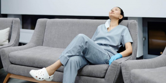 Photo of a tired healthcare professional resting on a grey couch