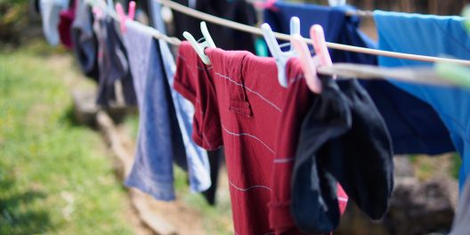 Colourful clothes hang on a clothes line on a sunny day.