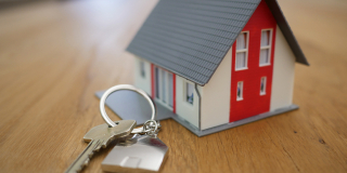 A tiny house key chain sits on a wooden table.