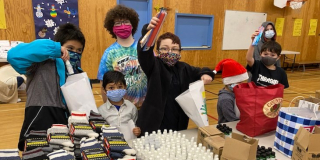 Kids cheer in front of a table full of warm clothes that have been donated to EDAS.